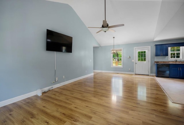 unfurnished living room with ceiling fan, light wood finished floors, a sink, and baseboards