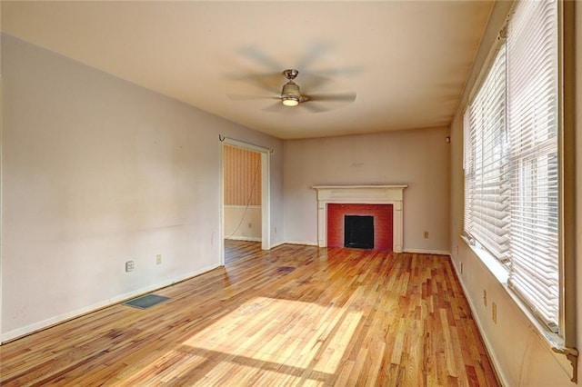 unfurnished living room with a fireplace, light wood-style floors, visible vents, and ceiling fan