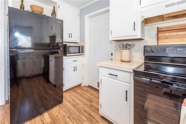 kitchen with white cabinetry, ornamental molding, light hardwood / wood-style flooring, and black appliances