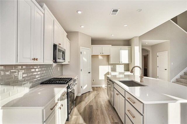 kitchen featuring sink, white cabinets, light hardwood / wood-style flooring, and appliances with stainless steel finishes