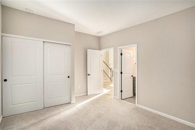 unfurnished bedroom with light colored carpet and a closet