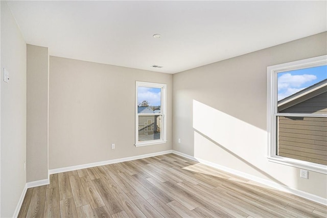 empty room with light hardwood / wood-style flooring and a wealth of natural light