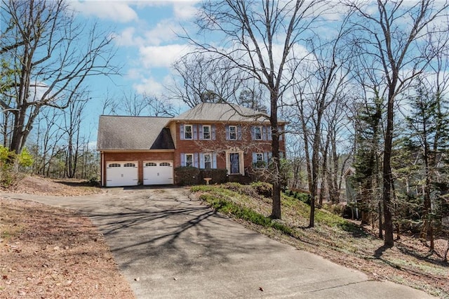 colonial home featuring driveway, a garage, and brick siding