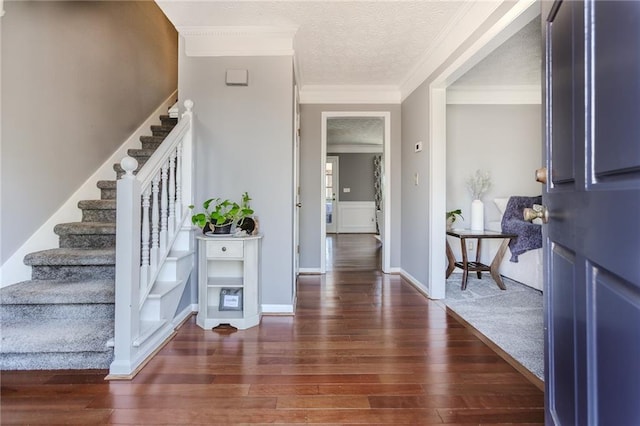 entryway with a textured ceiling, ornamental molding, stairway, and wood finished floors