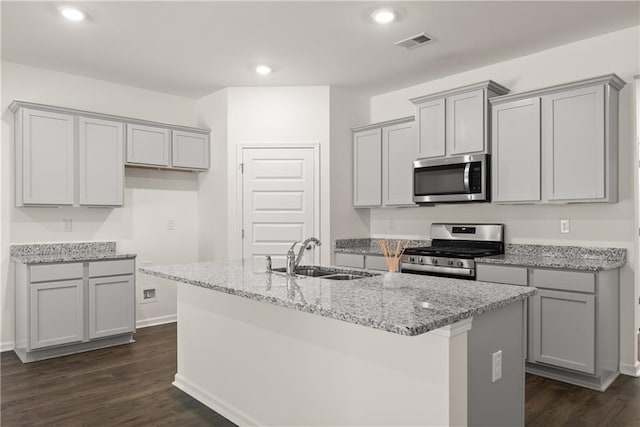 1278 Daurian Dr, Statham, GA 30666 - kitchen featuring stainless steel appliances, gray cabinetry, a kitchen island with sink, light stone countertops, and dark wood-type flooring