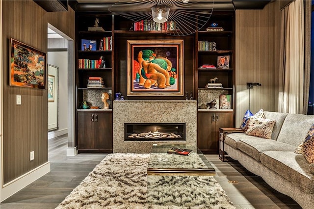 sitting room featuring wooden walls, a fireplace, built in features, and dark wood finished floors