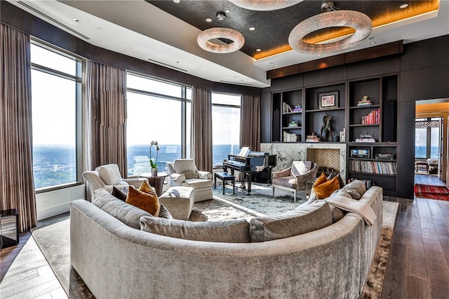 living area featuring built in features, a tray ceiling, hardwood / wood-style floors, and recessed lighting