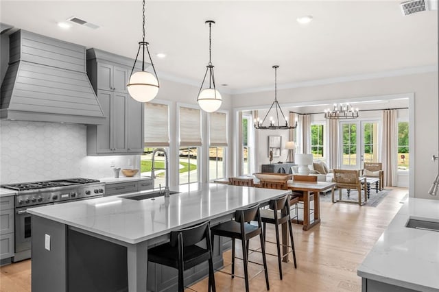 2031 Crossroads Trl, Milton, GA 30004 - kitchen with high end stainless steel range oven, gray cabinetry, a chandelier, custom range hood, and light stone counters