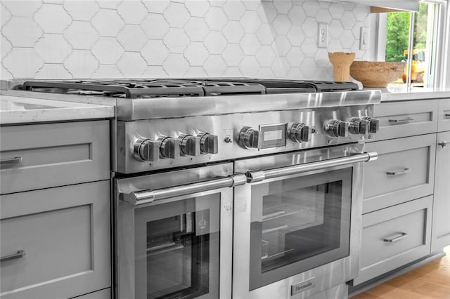 2031 Crossroads Trl, Milton, GA 30004 - kitchen with double oven range, decorative backsplash, gray cabinets, light stone counters, and light wood-type flooring