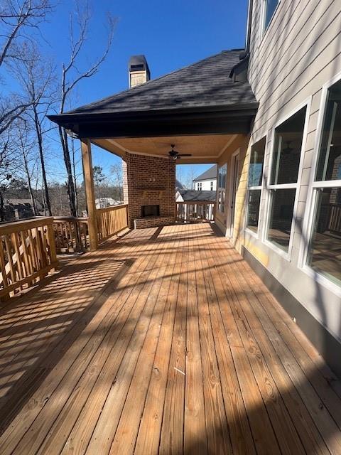 wooden terrace featuring ceiling fan and an outdoor brick fireplace