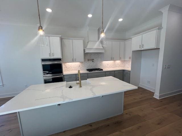 kitchen featuring white cabinets, decorative light fixtures, light stone counters, and custom range hood