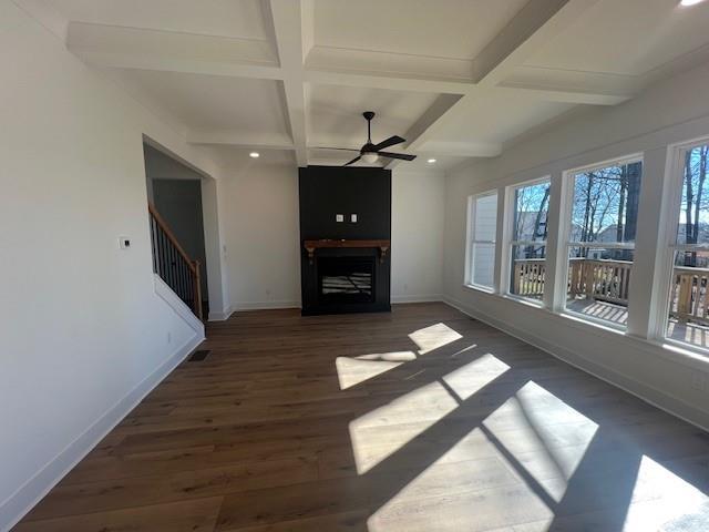 unfurnished living room featuring ceiling fan, a healthy amount of sunlight, beam ceiling, and coffered ceiling