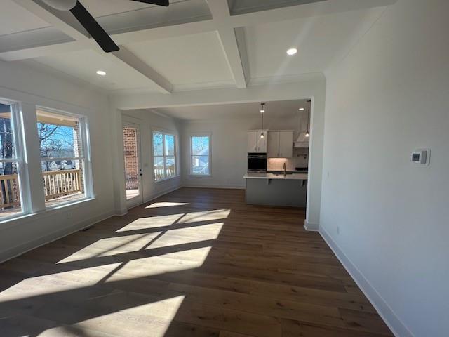 unfurnished living room with ceiling fan, beam ceiling, dark wood-type flooring, and coffered ceiling