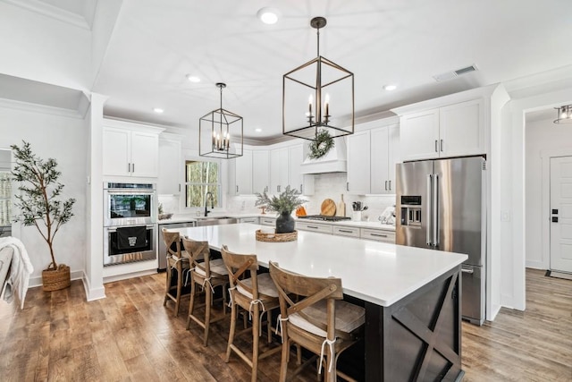 kitchen with appliances with stainless steel finishes, sink, a kitchen island, and white cabinets