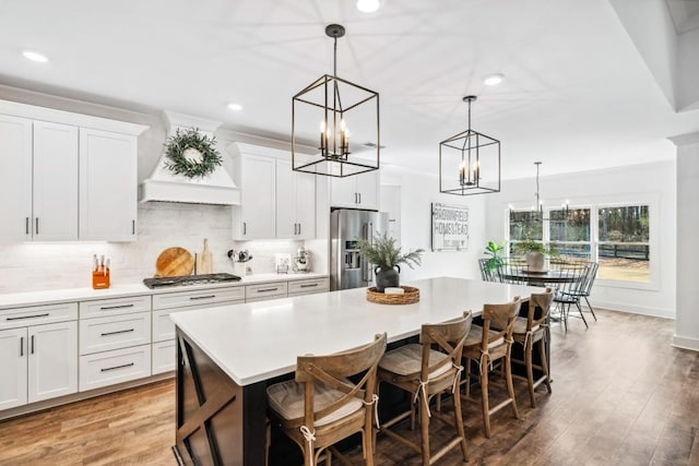 kitchen with a large island, pendant lighting, premium range hood, and appliances with stainless steel finishes