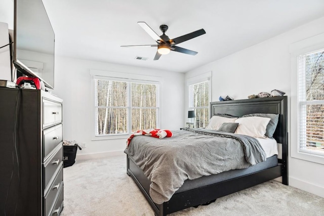 bedroom with ceiling fan, light colored carpet, and multiple windows