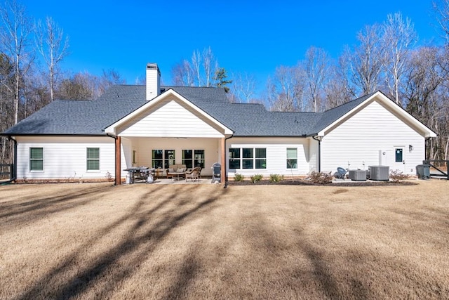 rear view of property with cooling unit, a yard, and a patio area