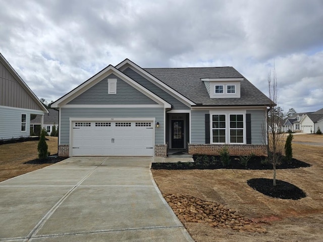 craftsman-style house featuring a garage, concrete driveway, brick siding, and roof with shingles