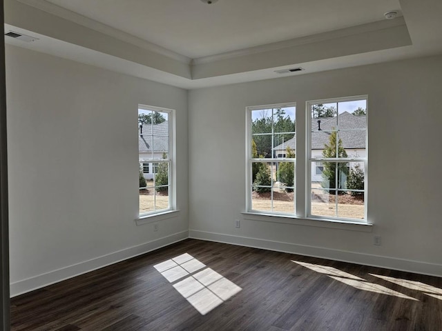 empty room with dark wood-style floors, a raised ceiling, visible vents, and baseboards