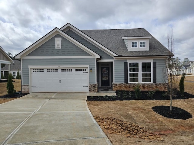 craftsman house with a shingled roof, brick siding, driveway, and an attached garage