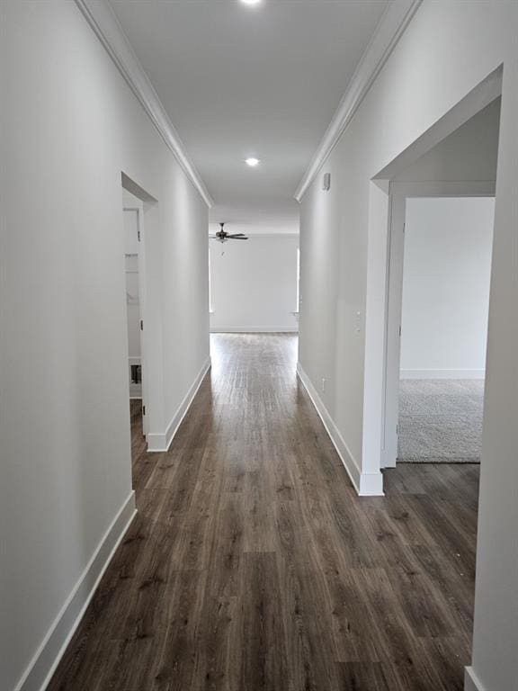 hallway featuring baseboards, ornamental molding, and dark wood-style flooring