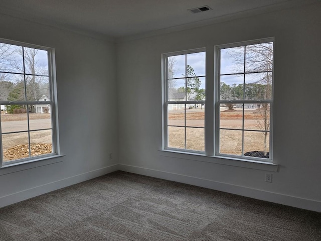 carpeted empty room featuring ornamental molding, visible vents, and baseboards