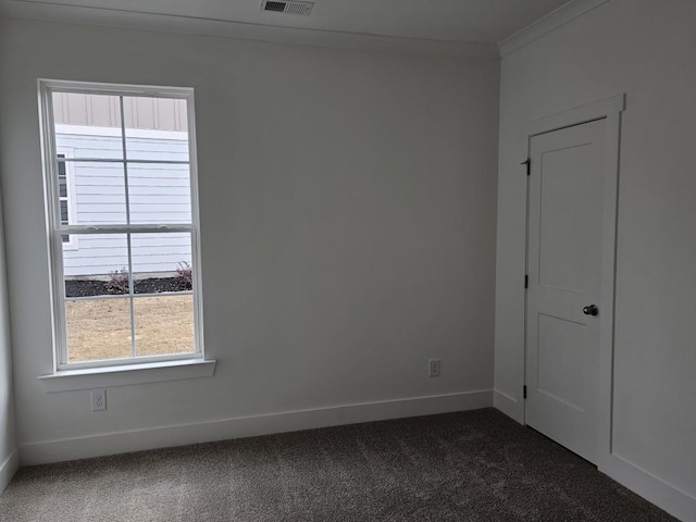 empty room with ornamental molding, carpet flooring, visible vents, and baseboards