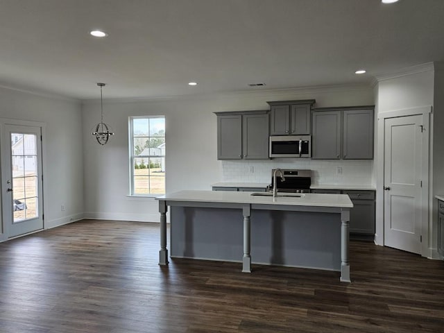 kitchen with a center island with sink, gray cabinetry, appliances with stainless steel finishes, dark wood-type flooring, and a sink