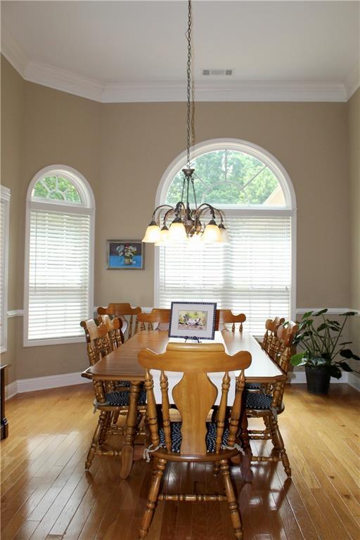 265 Mona Ct, Winder, GA 30680 - dining space with a chandelier, light wood-type flooring, healthy amount of natural light, and crown molding