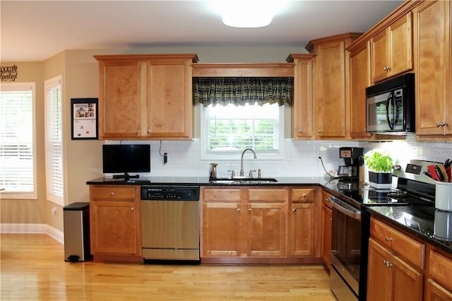 265 Mona Ct, Winder, GA 30680 - kitchen featuring stainless steel appliances, a sink, light wood-style floors, decorative backsplash, and baseboards