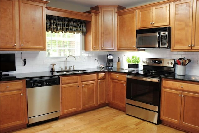 265 Mona Ct, Winder, GA 30680 - kitchen featuring stainless steel appliances, a sink, light wood finished floors, backsplash, and brown cabinets