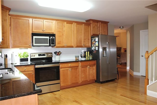 265 Mona Ct, Winder, GA 30680 - kitchen with appliances with stainless steel finishes, backsplash, light wood-type flooring, dark stone countertops, and baseboards