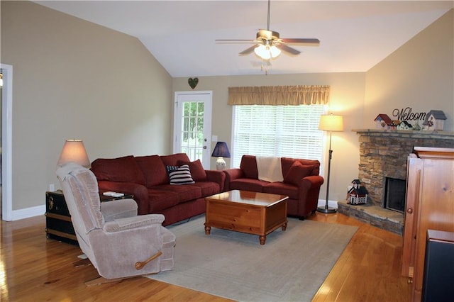 265 Mona Ct, Winder, GA 30680 - living area with light wood-style flooring, ceiling fan, vaulted ceiling, a stone fireplace, and baseboards