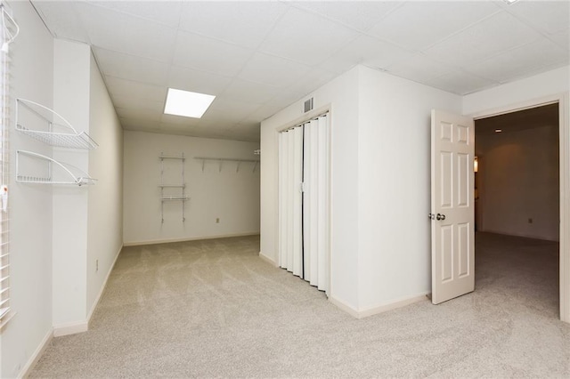 interior space with a paneled ceiling and light colored carpet