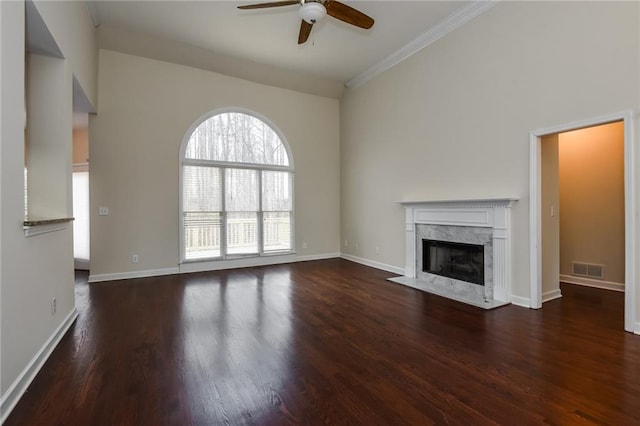 unfurnished living room featuring visible vents, a ceiling fan, wood finished floors, a high end fireplace, and baseboards