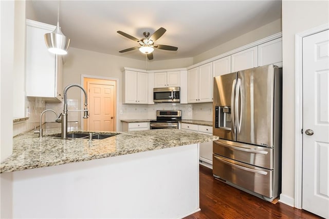 kitchen featuring sink, white cabinetry, kitchen peninsula, light stone countertops, and appliances with stainless steel finishes