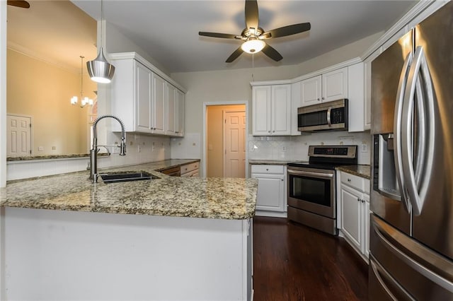 kitchen with kitchen peninsula, pendant lighting, white cabinets, appliances with stainless steel finishes, and sink