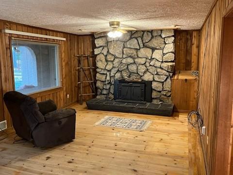 living area featuring a textured ceiling, wood walls, a ceiling fan, and hardwood / wood-style flooring