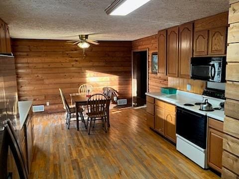 kitchen featuring wood finished floors, a ceiling fan, electric range, light countertops, and black microwave