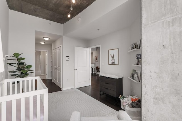 bedroom with a crib, dark hardwood / wood-style flooring, and a closet