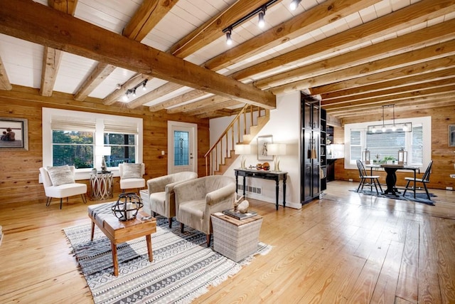 living room featuring wooden walls, beamed ceiling, light hardwood / wood-style floors, and track lighting