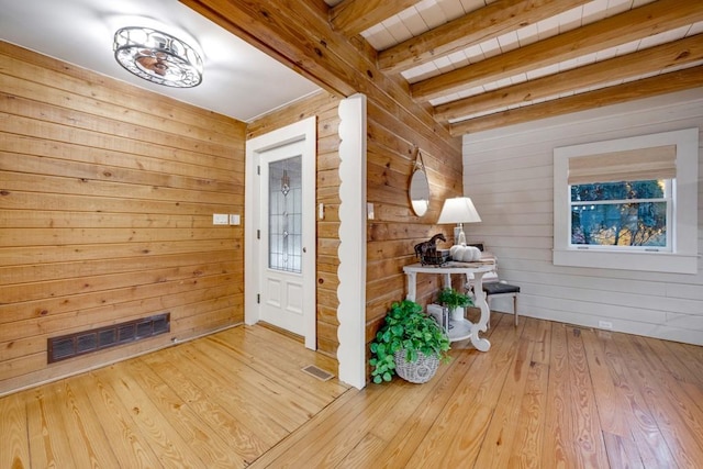 entryway featuring beam ceiling, wood walls, and light hardwood / wood-style floors