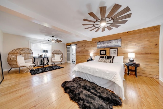 bedroom with beam ceiling, ceiling fan, wooden walls, and light hardwood / wood-style floors