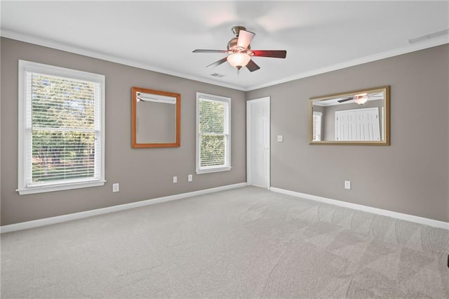 carpeted empty room featuring ceiling fan, visible vents, ornamental molding, and baseboards