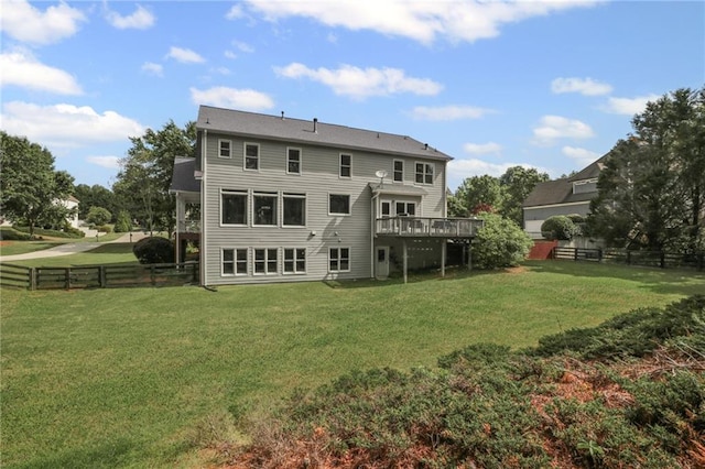 rear view of house with a lawn, fence, and a deck