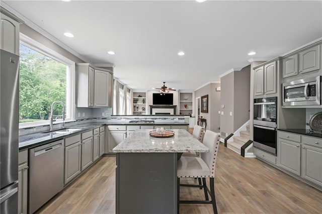 kitchen with a ceiling fan, crown molding, a sink, gray cabinetry, and stainless steel appliances