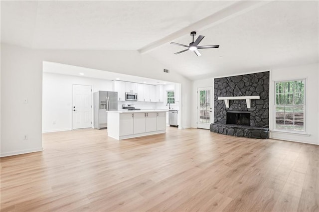 unfurnished living room featuring lofted ceiling with beams, light wood-style floors, a ceiling fan, baseboards, and visible vents