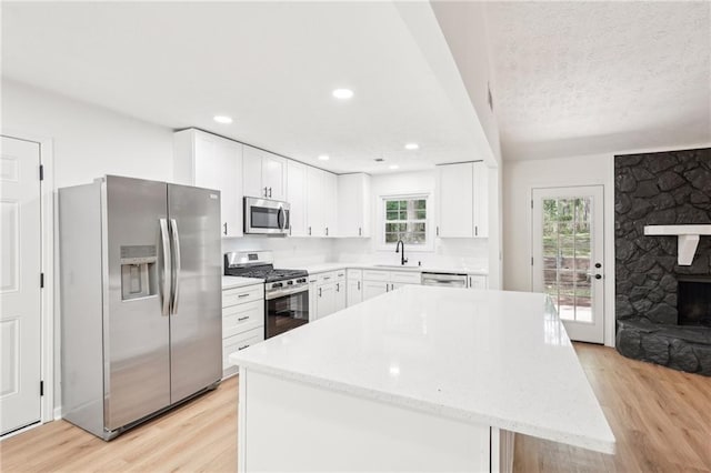 kitchen with light wood-type flooring, a sink, appliances with stainless steel finishes, and a center island