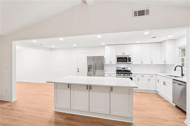 kitchen with visible vents, appliances with stainless steel finishes, a center island, a sink, and light countertops