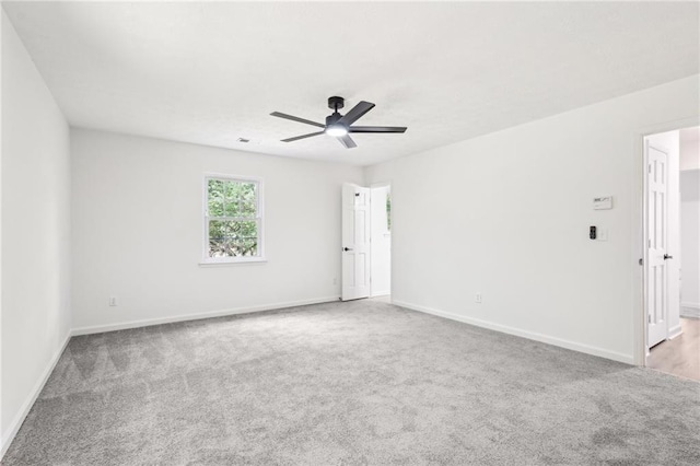 carpeted empty room with baseboards, a ceiling fan, and visible vents